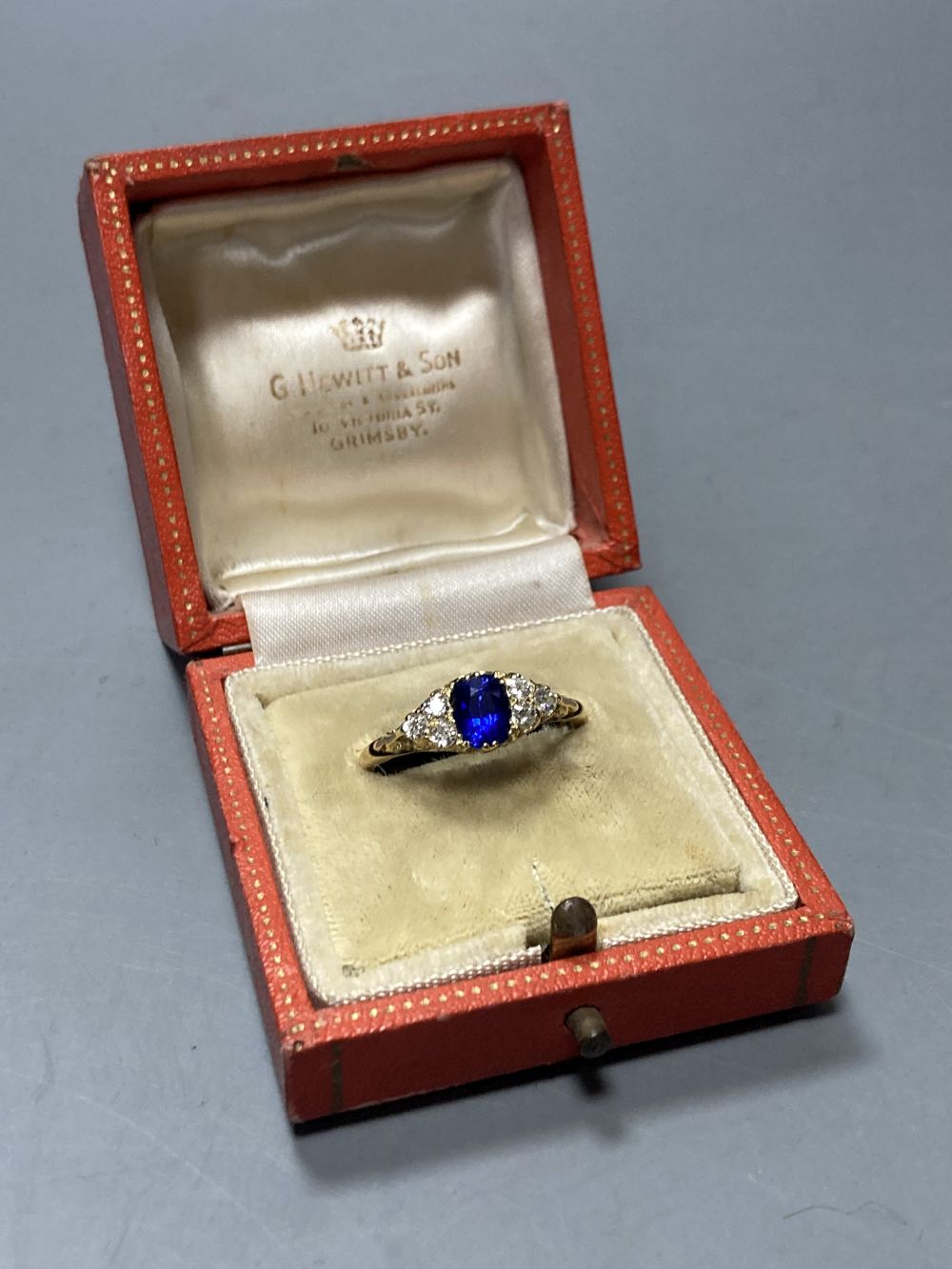 An 18ct, single stone sapphire and six stone diamond cluster ring, size U, gross 3.9 grams.